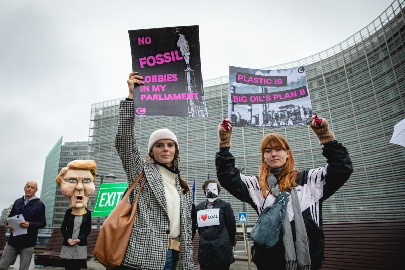 Two young activists holding signs saying ¨No fossil lobbies in my Parliament" and "Plastic is Big Oil's plan B" in a rally in front of the EU Commission. 