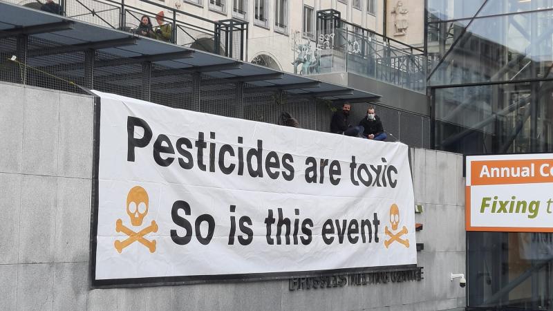 Banner saying with the symbols of poison: Pesticides are toxic. So is this event.