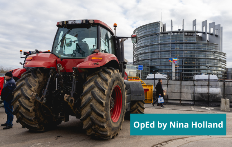 A picture of a red tractor in front of the European Parliament in Strasbourg. A person is walking and another one is standing by the tractor. On the bottom-right corner a turquoise box reads: OpEd by Nina Holland 